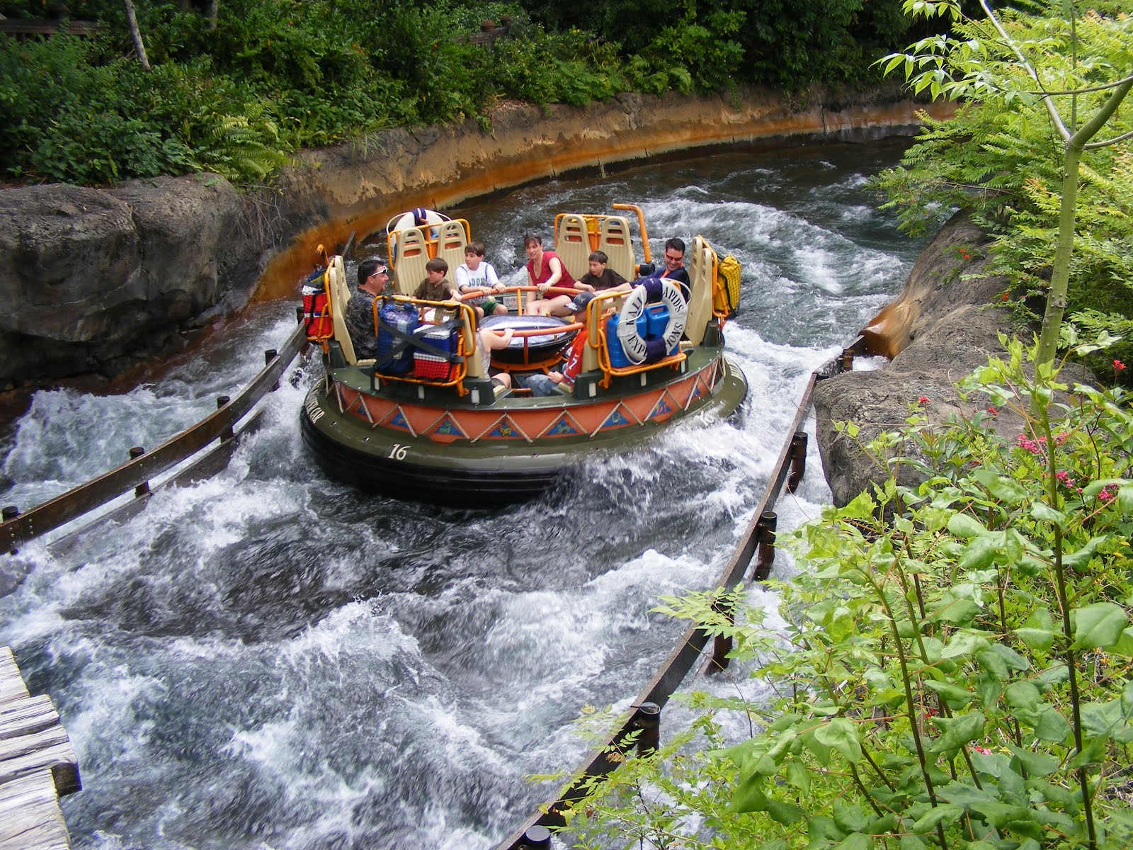 Families riding a circular river rapids raft through whitewater at a theme park