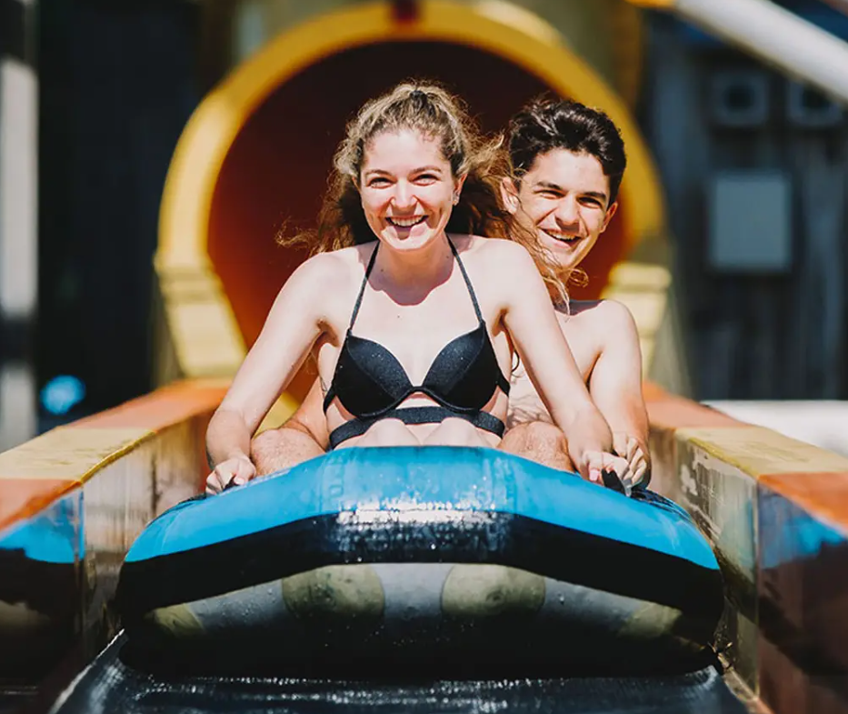 Two riders on a blue CPI Amusement two-person raft going down a water slide